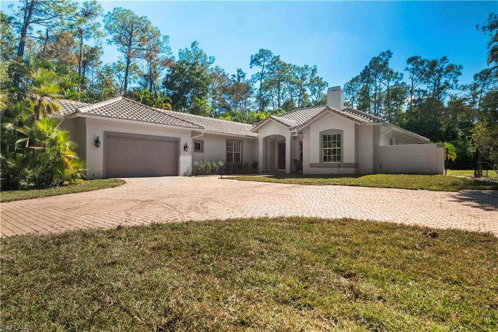 Mediterranean / spanish home featuring decorative driveway, stucco siding, a chimney, a front lawn, and an attached garage
