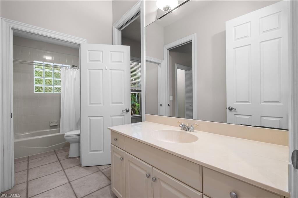 6800 Hunters Road Naples, FL 34109 - Photo 12 of 16 Bathroom featuring vanity, shower / bathtub combination with curtain, and light tile patterned floors