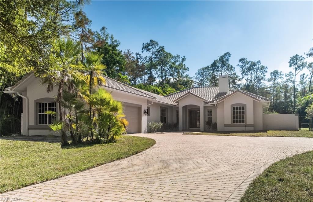 6800 Hunters Road Naples, FL 34109 - Photo 2 of 16 View of front facade with stucco siding, decorative driveway, an attached garage, and a chimney