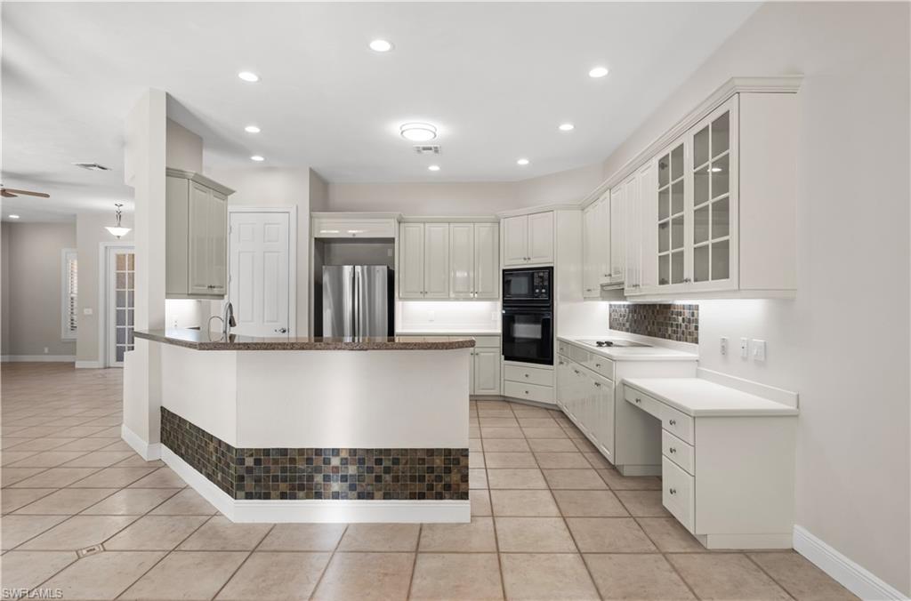 6800 Hunters Road Naples, FL 34109 - Photo 4 of 16 Kitchen featuring light tile patterned flooring, glass insert cabinets, black appliances, a peninsula, and recessed lighting