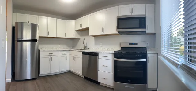 a kitchen with stainless steel appliances granite countertop a refrigerator stove a sink and dishwasher with wooden floor