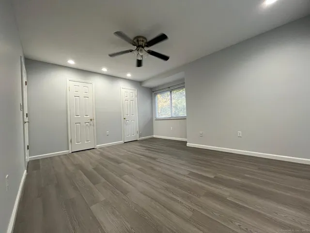 a view of an empty room with a window and wooden floor
