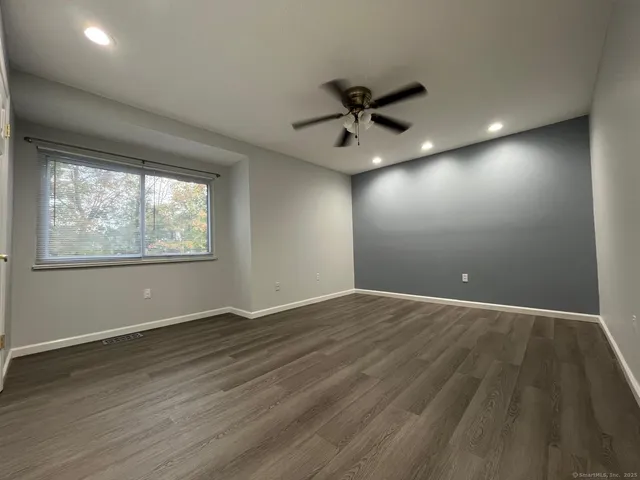 a view of an empty room with a window and wooden floor