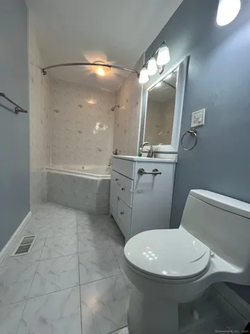 a white toilet sitting next to a bathroom sink and a mirror