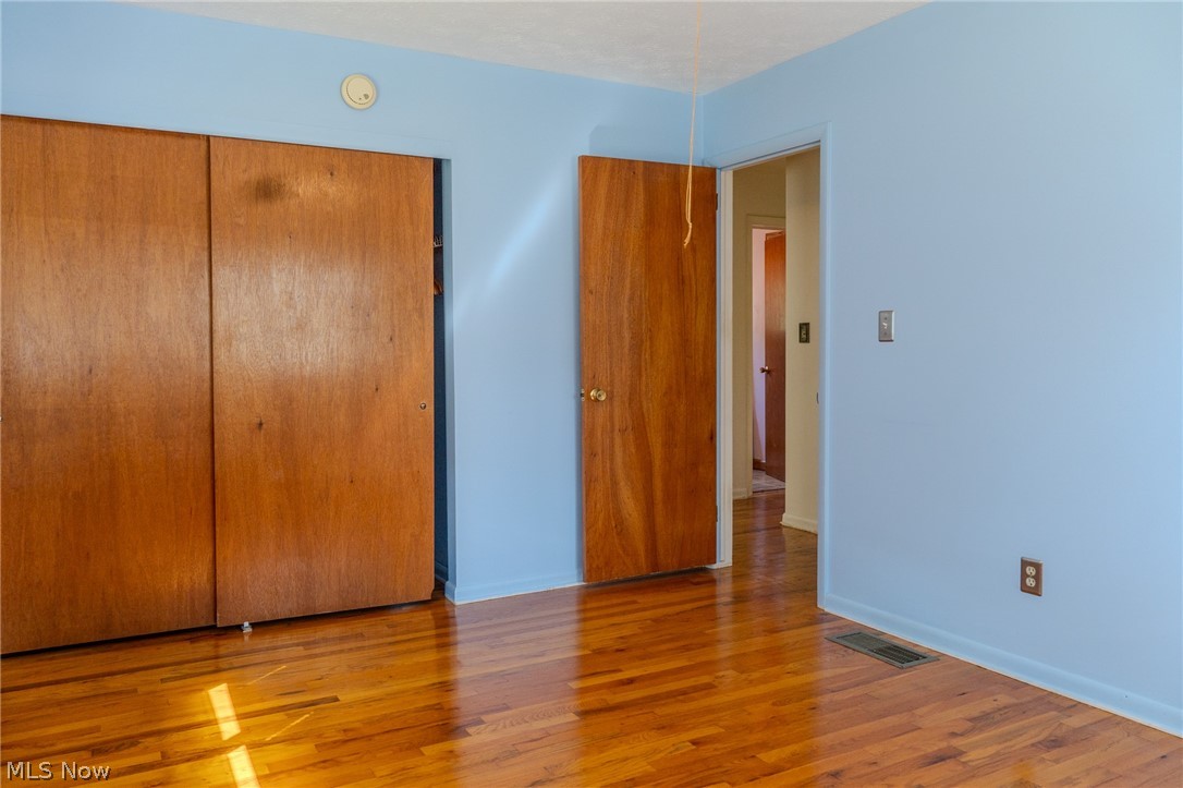 2848 Pressler Road Uniontown, OH 44685 - Photo 12 of 37 Hardwood flooring, wood-finish bi-fold closet doors, wood-finish interior door, and light blue painted walls