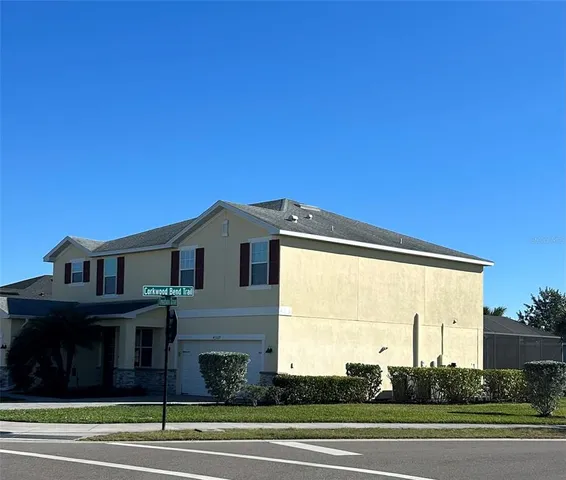 a view of a big house with a big yard and large trees