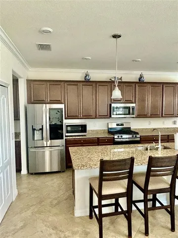 a kitchen with stainless steel appliances a stove a refrigerator island and chairs
