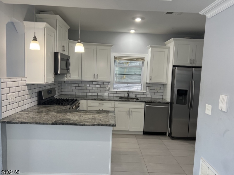 454 3rd Avenue Elizabeth Port, NJ 07206 - Photo 3 of 11 a kitchen with stainless steel appliances granite countertop a sink stove and refrigerator