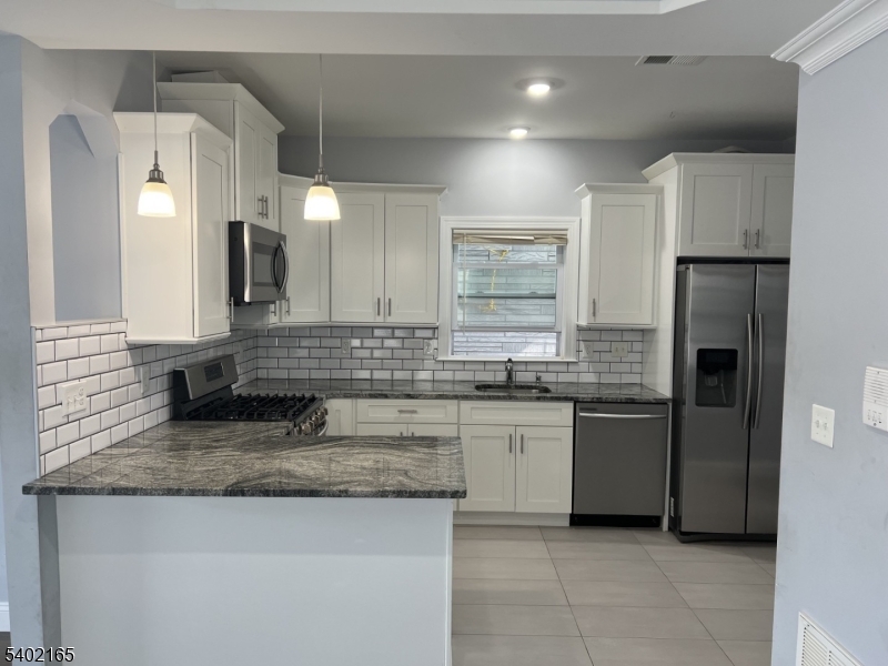 454 3rd Avenue Elizabeth Port, NJ 07206 - Photo 5 of 11 a large kitchen with granite countertop a sink and a refrigerator