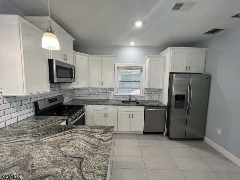 454 3rd Avenue Elizabeth Port, NJ 07206 - Photo 9 of 11 a kitchen with a sink a refrigerator and a stove top oven