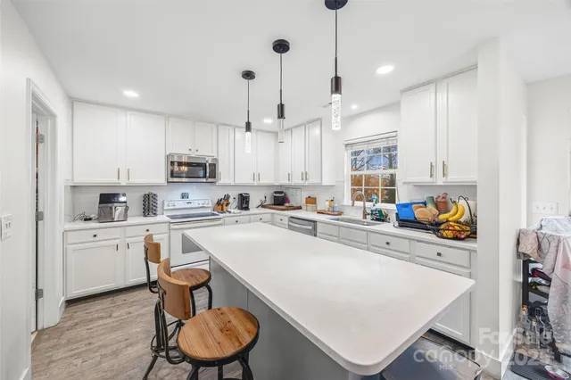 a kitchen with stainless steel appliances a white refrigerator a stove a sink a dining table and chairs