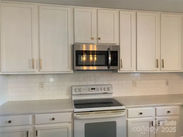 a kitchen with granite countertop white cabinets and stainless steel appliances