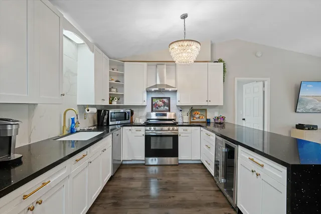 a kitchen with stainless steel appliances a stove refrigerator cabinets and wooden floor