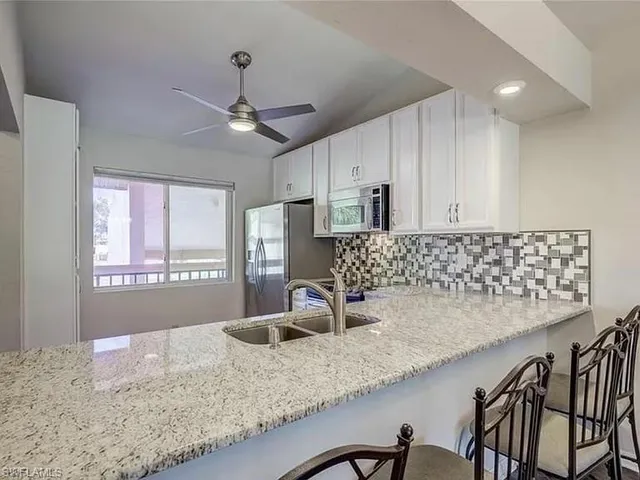 a kitchen with granite countertop a sink a window and stainless steel appliances