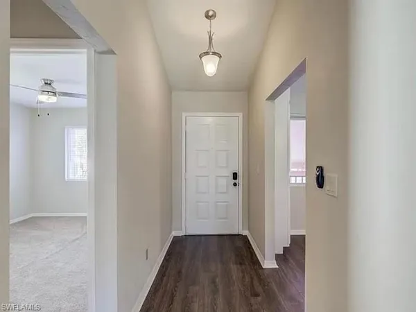 a view of a hallway with wooden floor and a bathroom