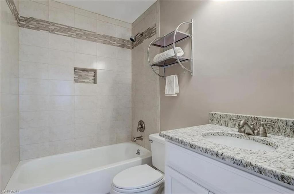 13130 White Marsh Lane, Unit 207 Fort Myers, FL 33912 - Photo 9 of 15 a bathroom with a granite countertop sink a toilet and bathtub