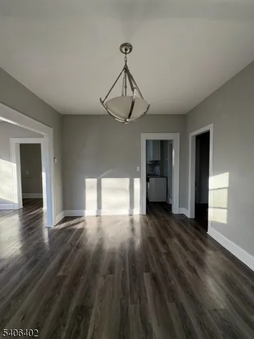 a view of empty room with wooden floor and window