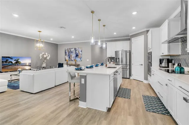 a large white kitchen with lots of counter space a sink appliances and cabinets