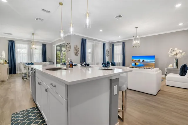 a large white kitchen with a large island oven a sink dishwasher and a stove with wooden floor