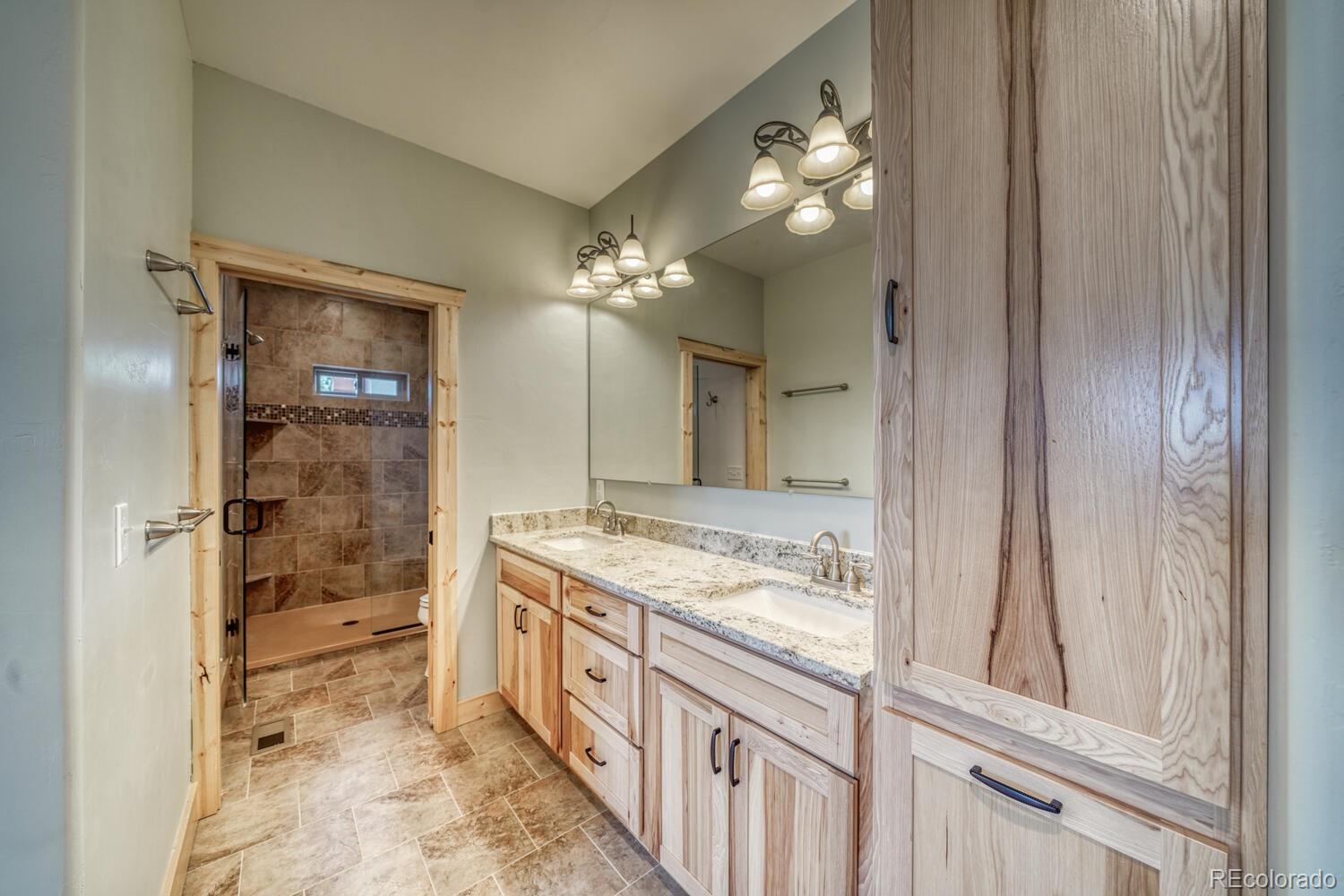 3561 Singletree Road Hartsel, CO 80449 - Photo 17 of 48 a bathroom with a granite countertop sink a mirror and a shower