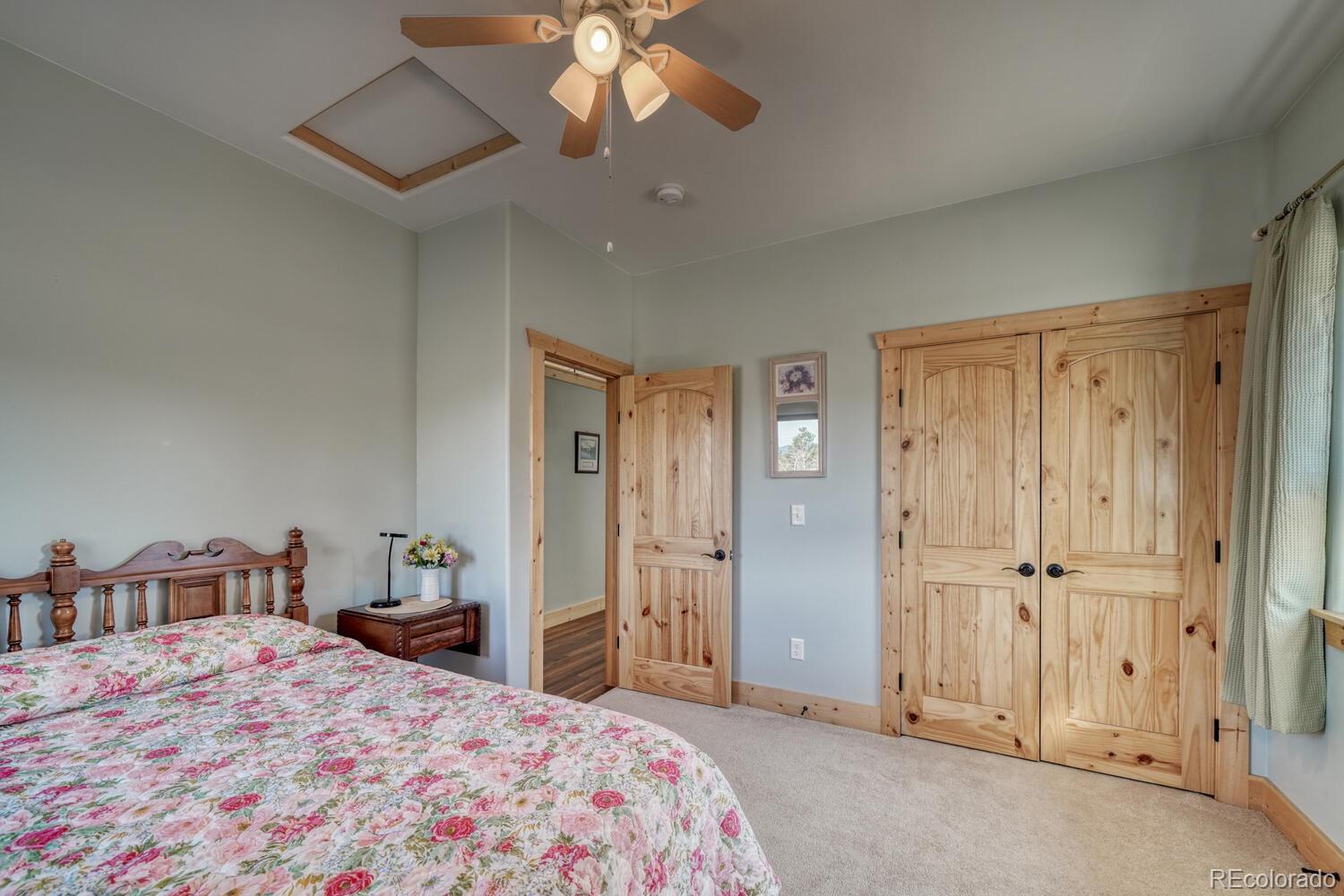 3561 Singletree Road Hartsel, CO 80449 - Photo 18 of 48 a bedroom with a large bed and a chandelier