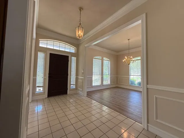 an empty room with wooden floor chandelier and windows