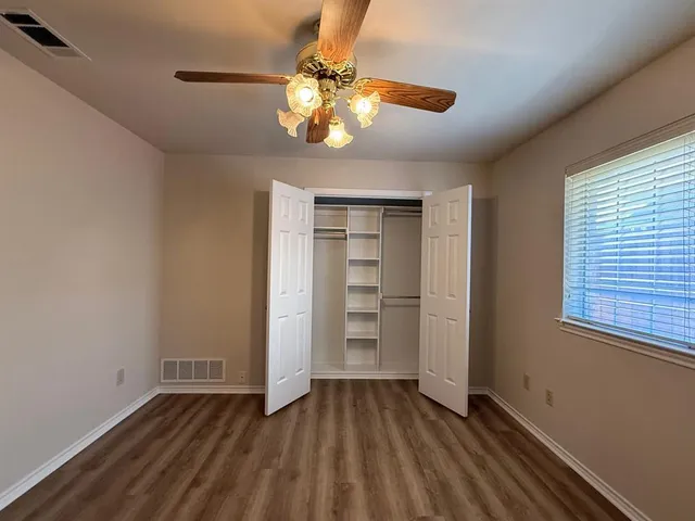 an empty room with wooden floor cabinet and windows