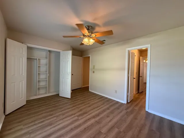 an empty room with wooden floor and a ceiling fan