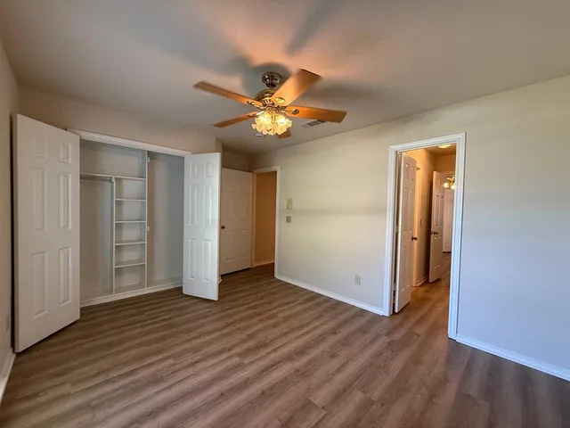 an empty room with wooden floor and a ceiling fan