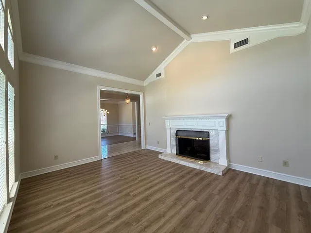 an empty room with wooden floor fireplace and windows