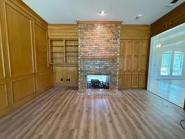 a view of empty room with wooden floor and fireplace