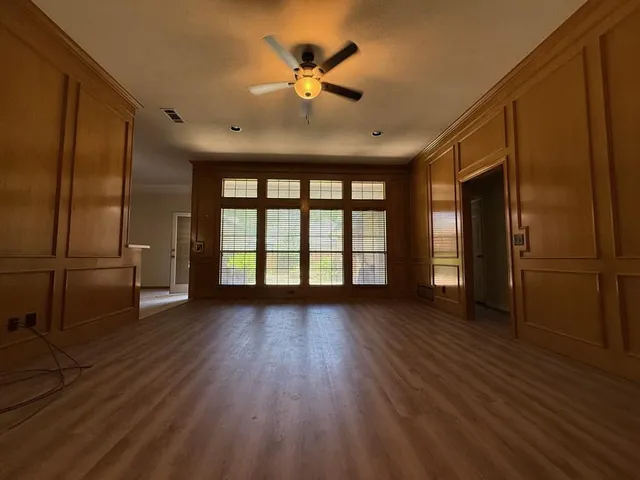 a view of an empty room with a window and wooden floor