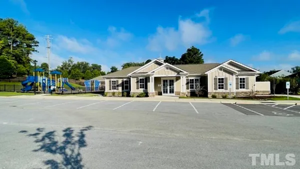 a view of white house with a yard and table and chairs under an umbrella