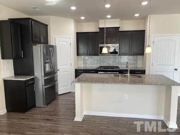a kitchen with stainless steel appliances granite countertop a refrigerator a stove and a sink