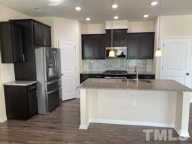 a kitchen with stainless steel appliances granite countertop a refrigerator a stove and a sink