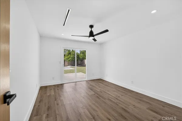 an empty room with wooden floor ceiling fan and windows