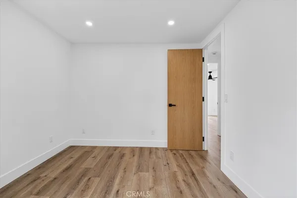 a view of an empty room with wooden floor and closet