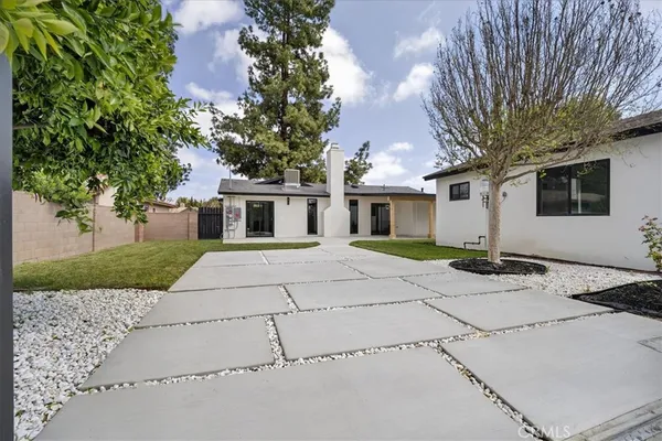 a view of a white house with a large tree