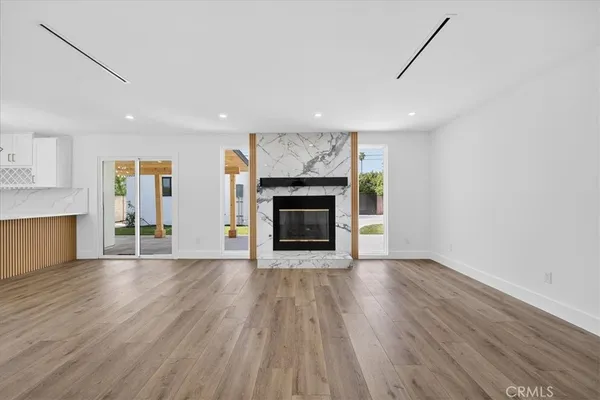 a view of an empty room with wooden floor fireplace and a window