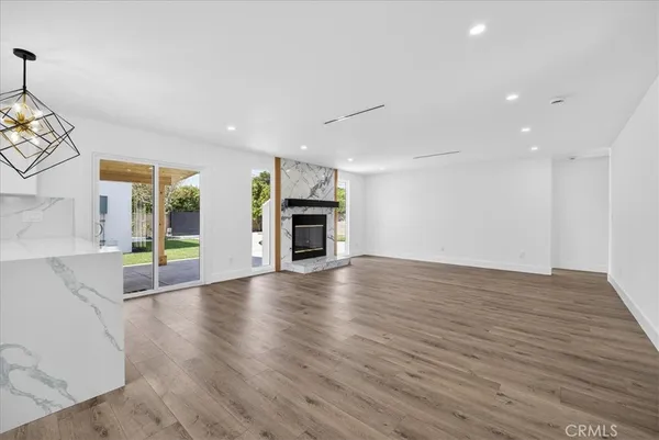 an empty room with wooden floor fireplace and windows