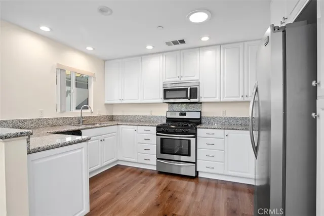 a kitchen with granite countertop a sink stainless steel appliances and cabinets