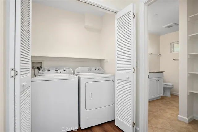 a view of washer and dryer with bathroom in the background