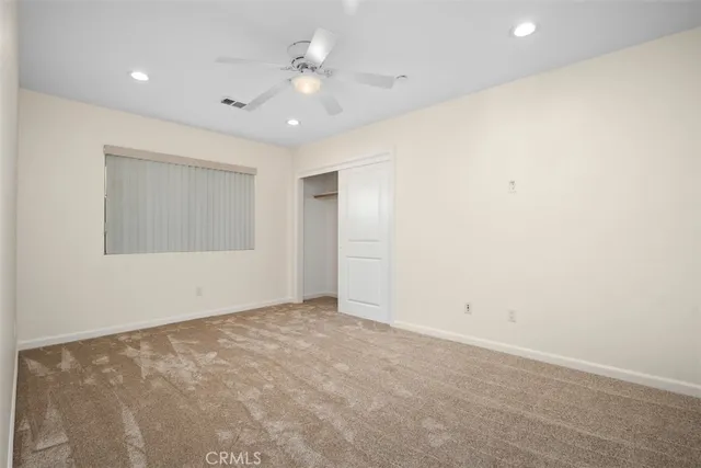 an empty room with a ceiling fan and a window