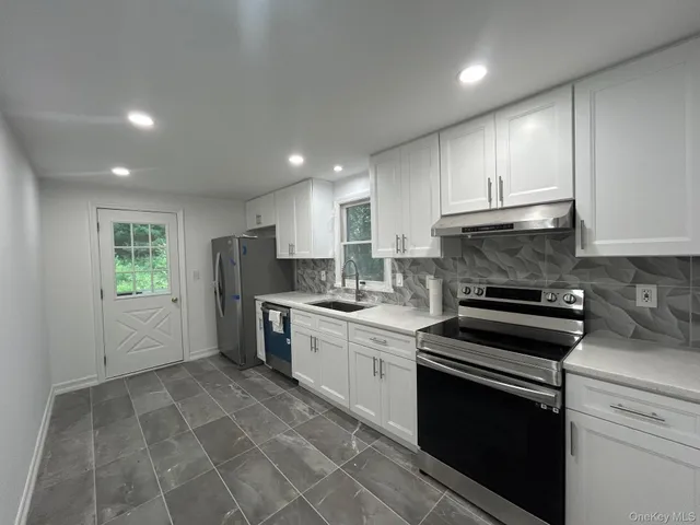 a kitchen with stainless steel appliances granite countertop a stove a sink and a refrigerator