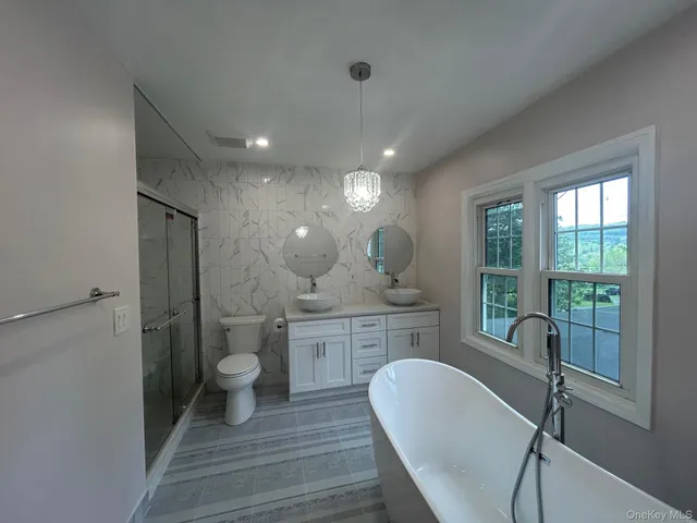 a spacious bathroom with a granite countertop sink a toilet a mirror and a tub