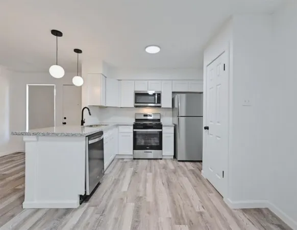 a kitchen with granite countertop a stove top oven and cabinets