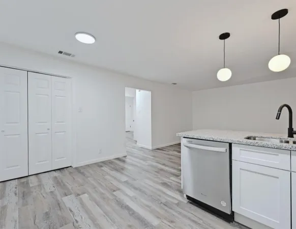 a view of a kitchen with white wooden cabinets