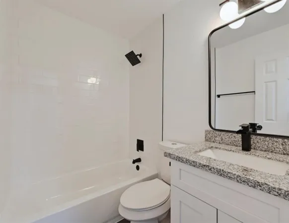 a bathroom with a granite countertop sink a toilet and shower
