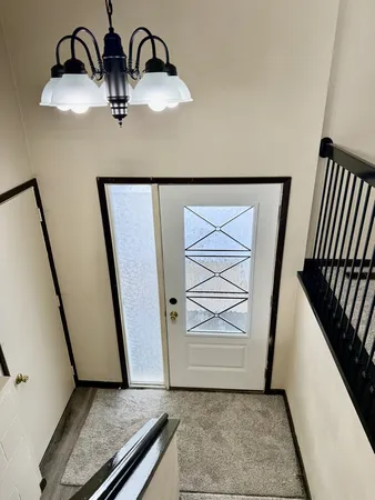 a view of a hallway with a dining space chandelier and stairs