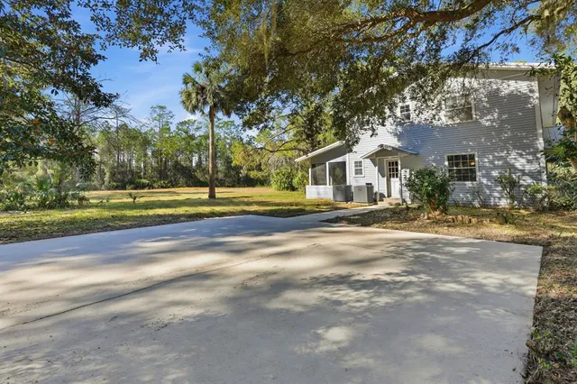 a front view of a house with a big yard and large trees